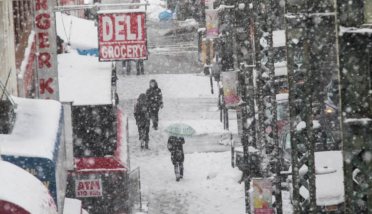 Pejalan kaki berjalan di tengah badai salju di sepanjang rel kereta di Broadway di distrik Brooklyn, New York (21/3). Badai salju yang melanda sebagian Amerika Serikat telah membawa salju dan angin kencang. (AP Photo / Mary Altaffer)
