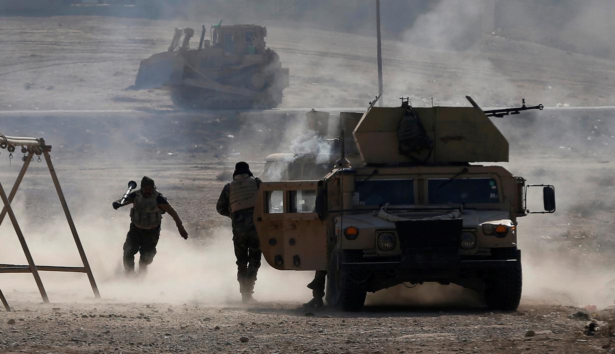 Tentara Irak berlari berlindung dibalik kendaraan militer setelah menembakan RPG saat bertempur melawan ISIS di Al-Qasar, Tenggara Mosul, Irak, (28/11). (REUTERS/Goran Tomasevic)