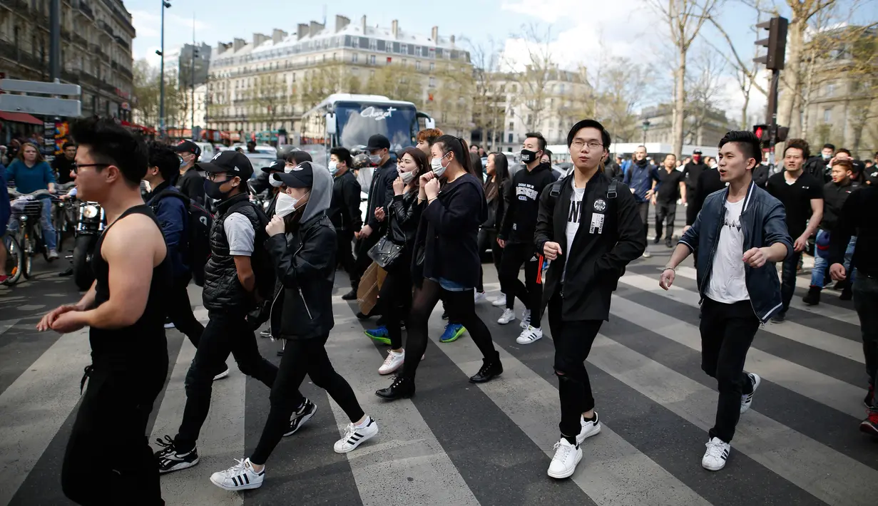 Sejumlah massa berjalan memadati Place de la Republique saat menggelar aksi, Paris, Prancis (2/4). Aksi mereka ini dipicu oleh kematian pria bernama Shaoyo Liu, 56, yang diduga tewas di tangan polisi. (AFP/Benjamin Cremel)