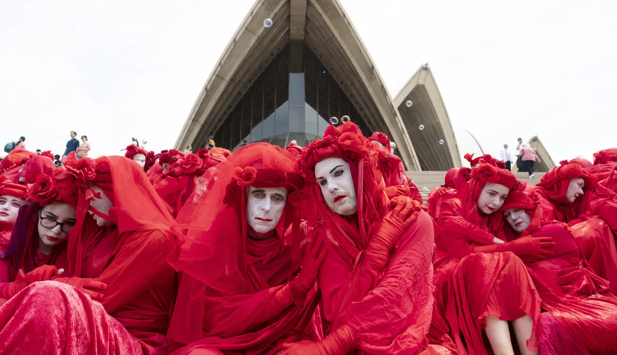 Aktivis yang terbagung dalam kelompok Red Rebels berunjuk rasa dalam demonstrasi protes iklim di Sydney (15/12/2019). Pengunjuk rasa melakukan aksi di depan landmark Gedung Opera Sydney menuntut pemerintah Australia menanggulangi asap yang menyebabkan masalah kesehatan. (AFP/Wendell Teodoro)