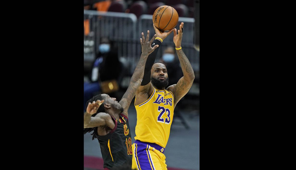 Pebasket LA Lakers, LeBron James (kanan) melempar bola ke ring dalam laga lanjutan babak reguler NBA melawan Cleveland Cavaliers di Quicken Loans Arena, Selasa (26/1/2021). (Foto: AP Photo/Tony Dejak)