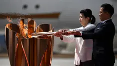 Atlet peraih tiga kali medali emas olimpiade, Tadahiro Nomura dan Saori Yoshida, menyalakan obor Olimpiade saat tiba dari Yunani di Pangkalan Udara Matsushima, Jepang, Jumat (20/3). Prosesi menuju Olimpiade Tokyo 2020 masih terus berjalan.(AFP/Philip Fong)