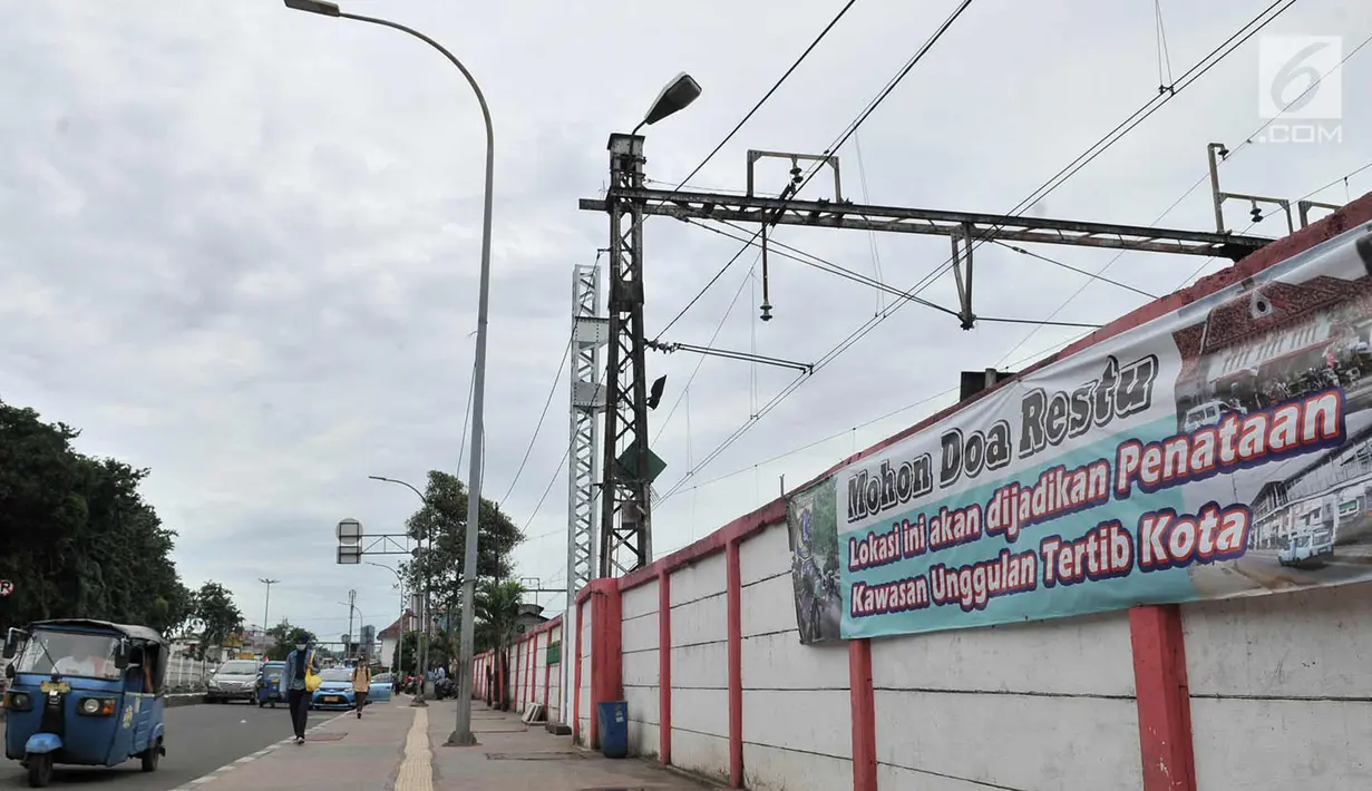 Kendaraan dan pejalan kaki melintas di depan spanduk bertuliskan "Mohon Doa Restu, Lokasi ini akan Dijadikan Kawasan Unggulan Tertib Kota" yang terpampang di sekitar Jatinegara, Jakarta Timur, Rabu (21/3). (Merdeka.com/Iqbal S. Nugroho)