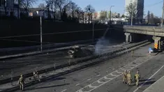 Tentara Ukraina berjalan di dekat puing-puing truk militer yang terbakar di sebuah jalan di Kyiv, Ukraina, Sabtu (26/2/2022). Pasukan Rusia menyerbu ke arah ibukota Ukraina Sabtu, dan pertempuran jalanan pecah saat pejabat kota mendesak penduduk untuk berlindung. (AP Photo/Efrem Lukatsky)