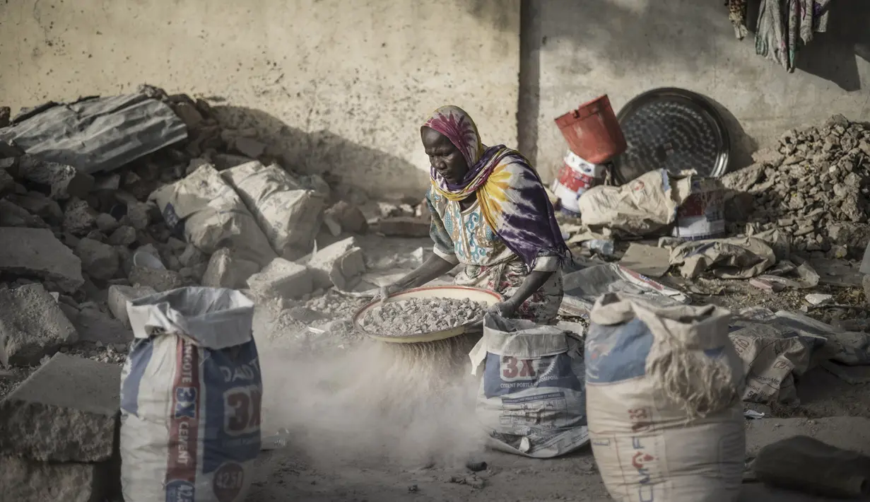 Habiba, penghancur kerikil berusia 50-60 tahun, mengayak dengan saringan improvisasi untuk memisahkan kerikil dari pasir di dekat Cite International des Affaires, N'Djamena, Chad, 12 April 2021. Dalam debu dan panas, wanita Chad menghancurkan kerikil untuk memenuhi kebutuhan. (MARCO LONGARI/AFP)