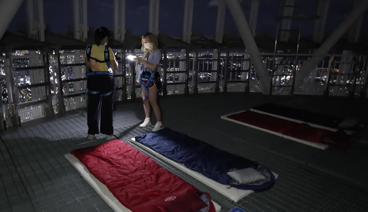 Orang-orang saat menginap di tempat berkemah semalam di atap gedung pencakar langit di Seoul, Korea Selatan (7/8/2020). Menara Lotte World membuka area berkemah jarak sosial di atap menara dan tanah untuk orang-orang yang jenuh di cuaca musim panas dan Covid-19. (AP Photo/Lee Jin-man)