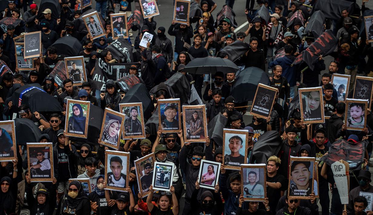 Pendukung sepak bola mengikuti aksi unjuk rasa memperingati 40 hari Tragedi Kanjuruhan, di depan balai kota Malang, Jawa Timur, Kamis (10/11/2022). Mereka membawa sejumlah keranda jenazah dengan foto-foto korban tragedi Kanjuruhan, dan poster berisi tuntutan. (JUNI KRISWANTO / AFP)