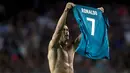 Pemain Real Madrid, Cristiano Ronaldo berselebrasi dengan melepas dan mengangkat jerseynya di hadapan suporter Camp Nou pada leg pertama Piala Super Spanyol, Senin (14/8). Selebrasi itu dilakukan usai Ronaldo membobol gawang Barcelona. (STRINGER/AFP)
