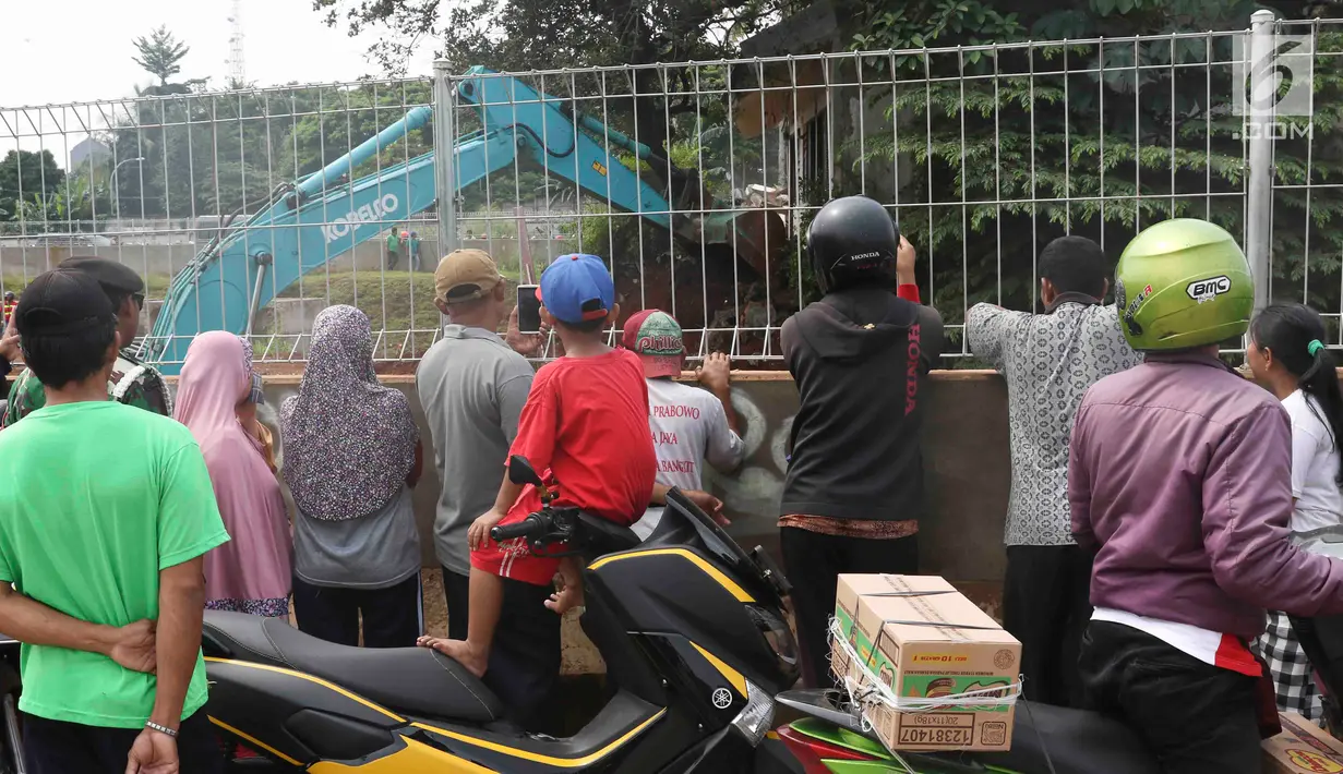 Warga menyaksikan alat berat mengeksekusi bangunan rumah milik warga yang terdampak proyek Jalan Tol Cijago Seksi II sepanjang 5,5 km di kawasan Kukusan, Depok, Jawa Barat, Rabu (12/12). (Liputan6.com/Immanuel Antonius)