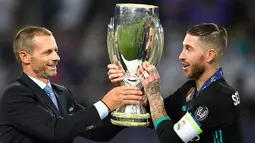 Presiden UEFA Aleksander Ceferin memberikan trofi Piala Super Eropa kepada bek Real Madrid, Sergio Ramos usai timnya menumbangkan Manchester United (MU) di Skopje, Macedonia, Selasa (8/8). Real Madrid mengalahkan MU dengan skor 2-1 (Dimitar DILKOFF / AFP)