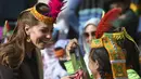 Duchess of Cambridge, Kate Middleton mengenakan topi tradisional suku Kalash tersenyum saat menerima hadiah dari seorang anggota suku Kalash selama kunjungannya ke Lembah Bumburate di Distrik Chitral utara Pakistan (16/10/2019). (AFP Photo/Farooq Naeem)