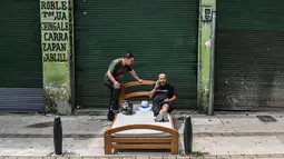 Dua pria bersantai di ranjang saat merayakan Hari Malas Sedunia di Itagui, dekat Medellin, Kolombia, Minggu (18/8/2019). Perayaan hari relaksasi selama seharian itu telah digelar setiap tahun sejak 1985 di kota kecil tersebut. (JOAQUIN SARMIENTO/AFP)