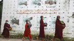 Biksu Buddha mengenakan masker berjalan melewati papan peringatan COVID-19 saat mereka mengumpulkan sedekah pagi di Yangon, Myanmar, Kamis (15/7/2021). Hampir 90 persen wilayah di Myanmar telah terkena dampak gelombang ketiga Covid-19. (AP Photo/Thein Zaw)