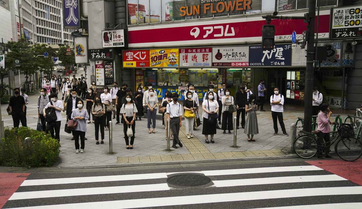 Komuter menunggu untuk menyeberang jalan menjelang Olimpiade 2020 di Tokyo, Jepang, Rabu (14/7/2021). Keadaan darurat akan berlaku sepanjang Olimpiade yang dibuka pada 23 Juli. (AP Photo/Jae C. Hong)