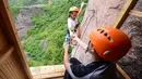 Seorang pemanjat tebing membeli air mineral di toko serba ada yang menempel di dinding tebing di Pingjiang di provinsi Hunan, China (25/4). (AFP Photo/China Out)