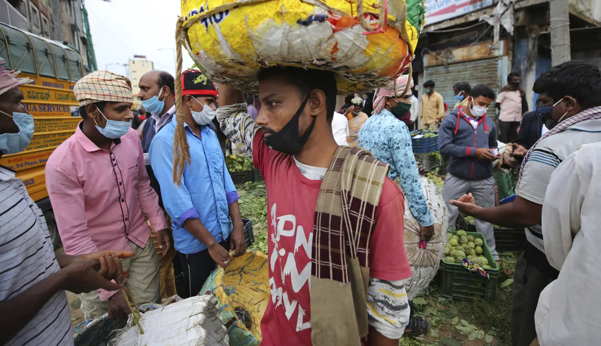 Pekerja upahan harian dan penjual buah mengenakan masker di pasar grosir di Bengaluru, India, Kamis (24/9/2020). Negara berpenduduk 1,3 miliar itu diperkirakan akan menjadi negara terparah pandemi COVID-19 dalam beberapa minggu, melampaui AS. (AP Photo/Aijaz Rahi)