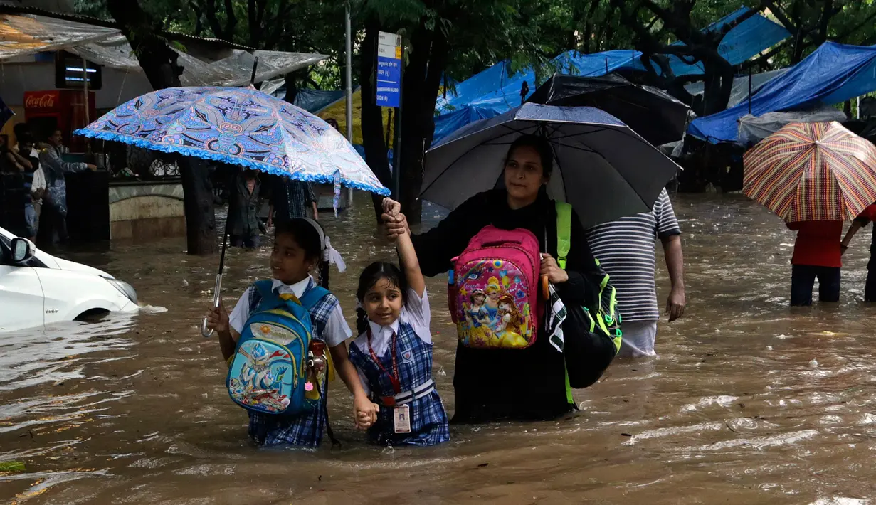 Dua anak sekolah menerobos jalanan yang terendam banjir akibat hujan lebat mengguyur kota Mumbai di India, Selasa (29/8). Air hujan juga membanjiri King Edward Memorial Hospital di Mumbai Tengah. (AP Photo/Rajanish Kakade)
