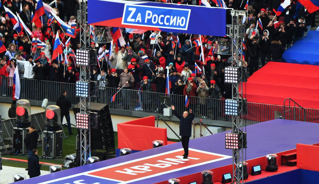 Presiden Rusia Vladimir Putin melambai kepada orang-orang yang berkumpul untuk menghadiri konser perayaan  delapan tahun referendum tentang status negara bagian Krimea dan Sevastopol serta penyatuannya kembali dengan Rusia, di Moskow, Rusia (18/3/2022). (Evgeny Biyatov/Sputnik Pool Photo via AP)