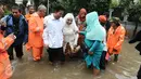 Keluarga pengantin dan pengantin Mansur dan Maya di evakuasi pasukan orange seusai melakukan akad nikah di KUA Mampang Prapatan, Jakarta, Selasa (21/2). Walaupun banjir sepasang pengantin ini tetap melakukan akad nikah. (Liputan6.com/Herman Zakharia)