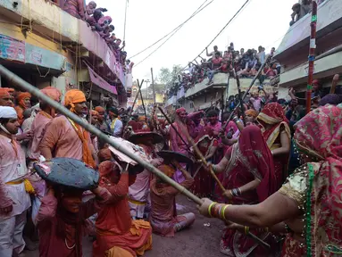 Sejumlah wanita memukul pria dengan tongkat (lathi) selama perayaan Lathmar Holi di Barsana di Mathura, India, (24/2). Lathmar Holi adalah perayaan lokal festival Hindu Holi, biasanya beberapa hari sebelum festival Holi. (AFP Photo/Dominique Faget)