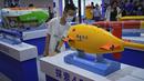 Seorang anak yang mengenakan masker melihat lebih dekat model kapal selam tak berawak buatan China yang dipamerkan di Konferensi Robot Dunia di Pusat Konferensi dan Pameran Internasional Yichuang di Beijing, Kamis (18/8/2022). (AP Photo/Andy Wong)