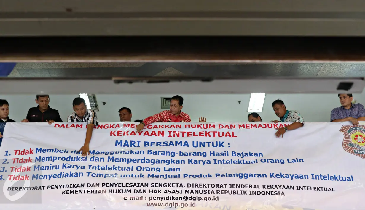 Petugas memasang spanduk sosialisasi peningkatan kesadaran untuk menghormati hasil karya intelektual di salah satu pusat perbelanjaan elektronik di Mangga Dua, Jakarta, Rabu (18/5).(Liputan6.com/Immanuel Antonius)
