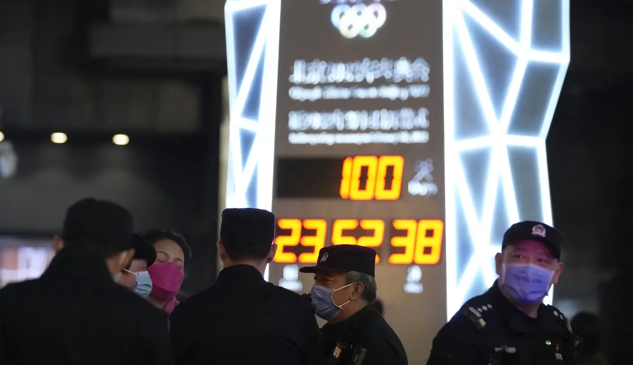 Petugas polisi berjaga-jaga di dekat jam hitung mundur 100 hari menuju pembukaan Olimpiade Musim Dingin Beijing 2022, di Beijing, China, Selasa (26/10/2021). Olimpiade Musim Dingin Beijing 2022 akan berlangsung 4 hingga 20 Februari. (AP Photo/Ng Han Guan)