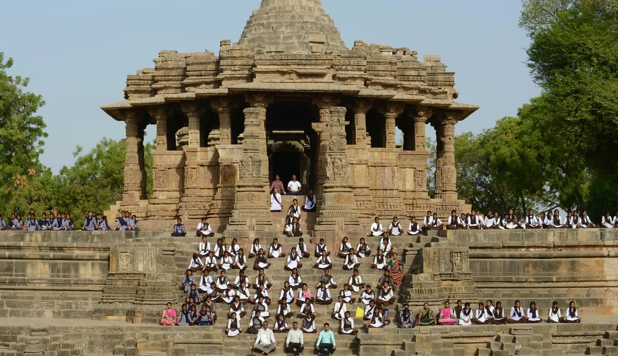 Para siswa mengikuti sesi yoga untuk menandai Hari Yoga Internasional di Kuil Matahari di Modhera, India (21/6). Kuil Matahari, sebuah kuil Hindu yang dibangun sekitar tahun 1026 M, adalah sebuah monumen yang dilindungi. (AFP Photo/Sam Panthaky)