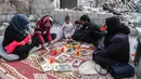 Keluarga Tareq Abu Ziad berbuka puasa di tengah reruntuhan rumah mereka yang hancur setelah serangan militer pasukan pemerintah dan sekutunya di Kota Ariha, Provinsi Idlib, Suriah, Senin (4/5/2020). Muslim Suriah melewati Ramadan tahun ini masih dalam kondisi perang. (AAREF WATAD/AFP)