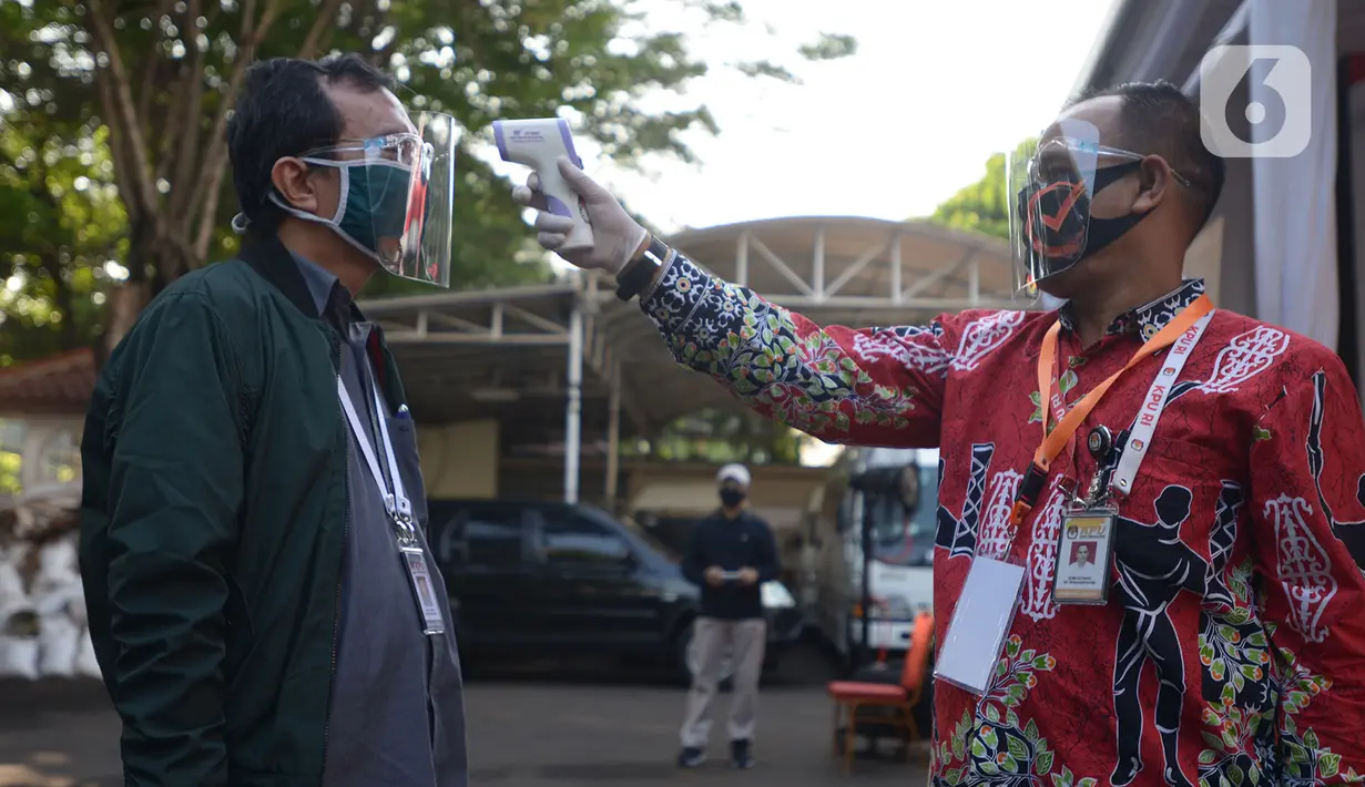 Petugas mengukur suhu tubuh saat simulasi pemungutan suara dalam pemilihan serentak 2020 di Halam Kantor KPU, Jakarta, Rabu (22/7/2020). Simulasi pemungutan suara di TPS dengan menerapkan protokol kesehatan Covid-19. (merdeka.com/Imam Buhori)