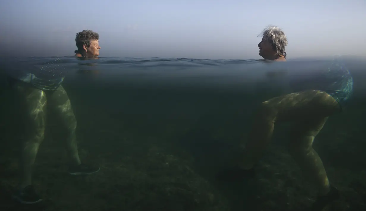 Pengunjung saat berenang di laut Havana, (28/4/2015). Badan dan kepala dari dua orang ini tampak ditempat yang berbeda. (REUTERS/Alexandre Meneghini)