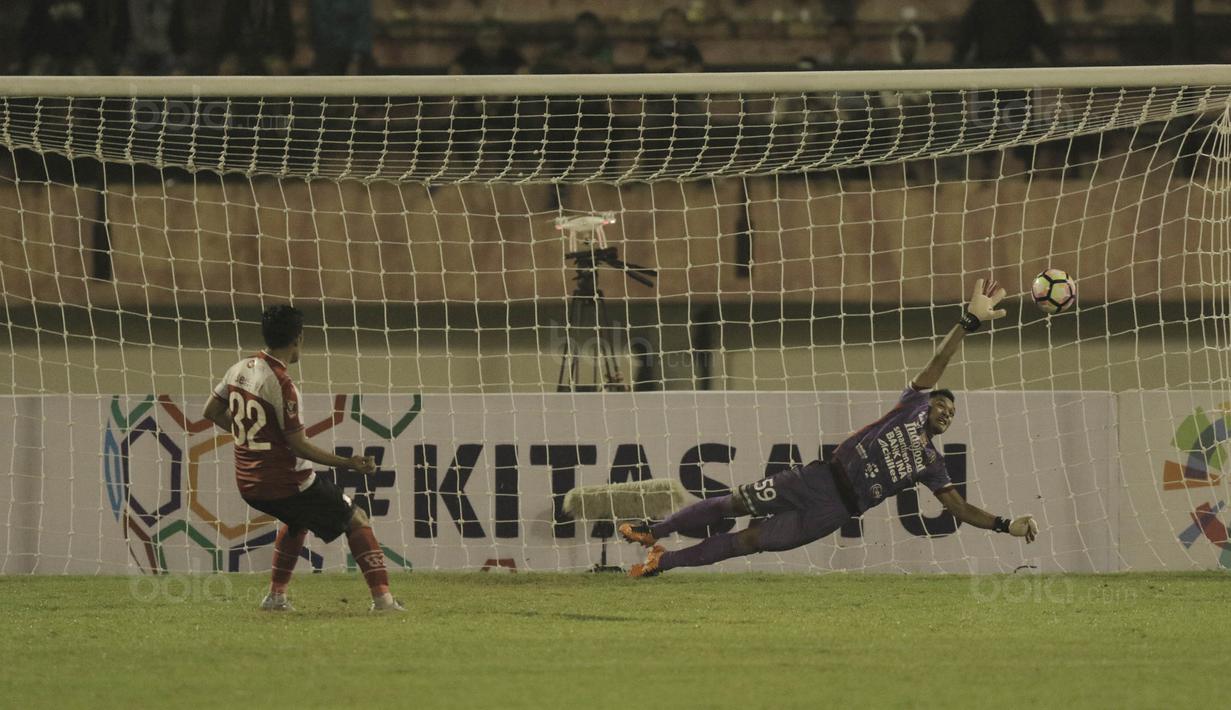 Kiper Bali United, Wawan Hendrawan, berusaha menghalau bola tendangan bek Madura United, Beny Wahyudi, pada laga Piala Presiden di Stadion Manahan, Solo, Sabtu, (3/2/2018). Bali United menang adu penalti dengan skor 5-4. (Bola.com/M Iqbal Ichsan)