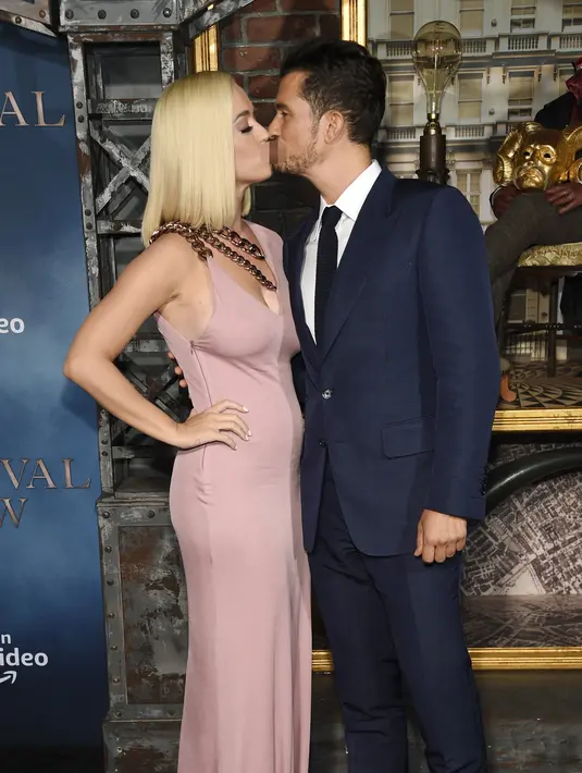 Penyanyi Katy Perry mencium pacarnya Orlando Bloom saat menghadiri pemutaran perdana untuk serial televisi "Carnival Row" di Los Angeles, California, AS (21/8/2019). Orlando Bloom tampil berjas biru tua dan kemeja putih berdasi hitam  dengan sepatu hitam mengilap. (AP Photo/Chris Pizzello)