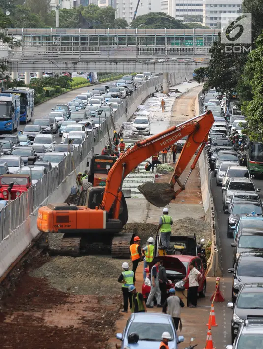 Sejumlah pekerja dibantu alat berat menggarap penataan jalan dan trotoar di Jalan Sudirman, Jakarta, Selasa (17/4). Trotoar tersebut akan dilebarkan menjadi 9 hingga 12 meter. (Liputan6.com/Arya Manggala)