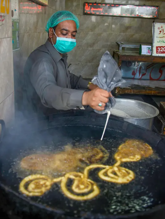 Seorang pria membuat jalebi manis di kiosnya pada hari pertama bulan suci Ramadhan di Rawalpindi, Pakistan, Sabtu (25/4/2020). (Photo by Farooq NAEEM/AFP)