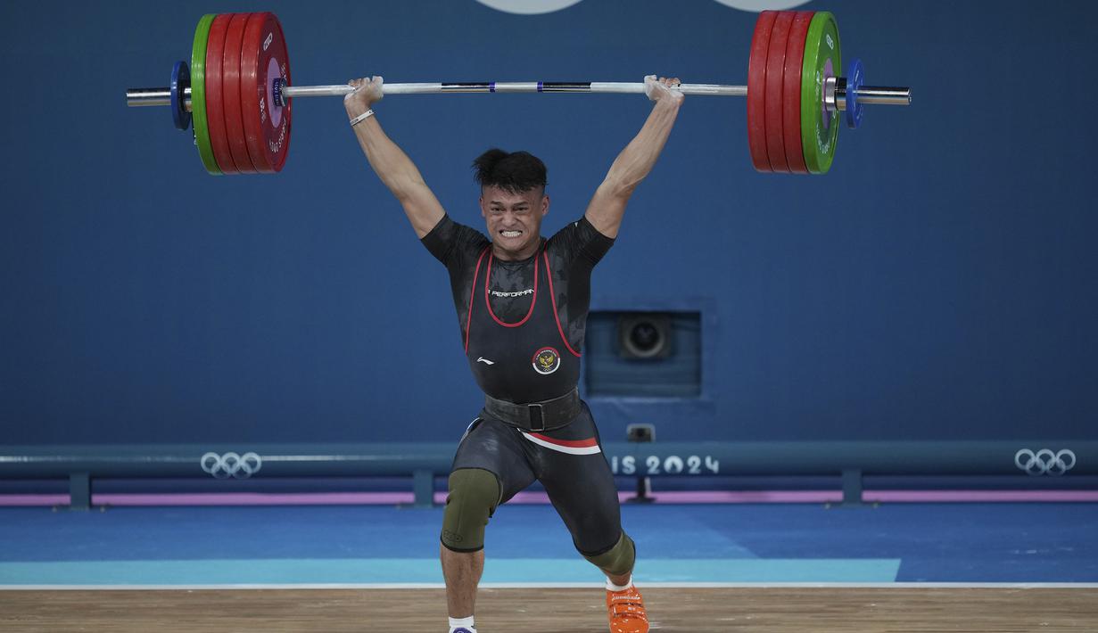 <p>Atlet angkat besi Indonesia, Rizki Juniansyah berhasil mengangkat beban seberat 199 kg pada angkatan clean and jerk saat berlomba pada kelas 73 kg putra cabor angkat besi Olimpiade Paris 2024 di Paris Expo Porte de Versailles, Paris, Kamis (8/8/2024). (AP Photo/Kin Cheung)</p>