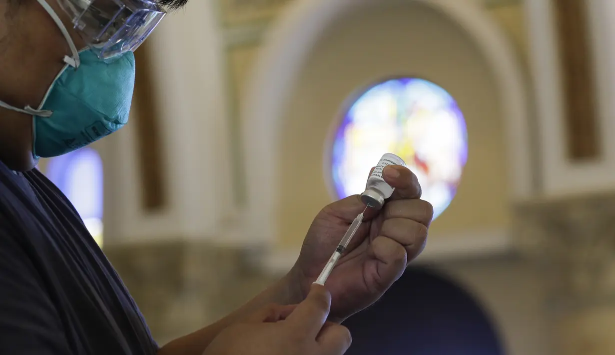 Seorang petugas kesehatan menyiapkan vaksin COVID-19 produksi AstraZeneca di dalam gereja Paroki Hati Kudus Yesus di Quezon City, Filipina, Senin (17/5/2021). Gereja itu digunakan untuk mempercepat proses vaksinasi kepada warga di daerah tersebut. (AP Photo/Aaron Favila)