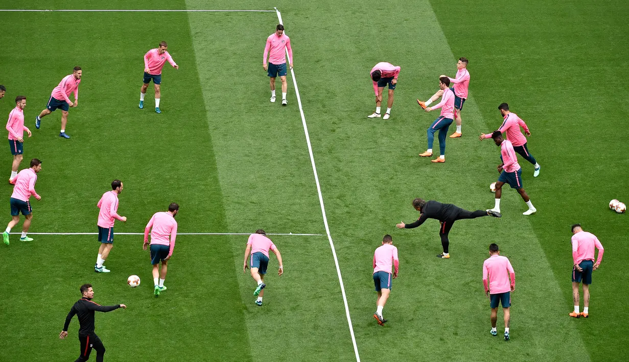 Para pemain Atletico Madrid melakukan pemanasan selama sesi latihan di stadion Parc OL di Decines-Charpieu (15/5). Atletico Madrid akan bertanding melawan wakil Prancis, Marseille pada babak final Liga Europa. (AFP Photo/Jean-Philippe Ksiazek)