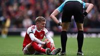 Gelandang Arsenal asal Norwegia #08, Martin Odegaard (kiri), Bereaksi setelah mengalami cedera dalam pertandingan&nbsp;Premier&nbsp;League&nbsp;antara Arsenal dan West Ham United di Stadion Emirates, London, pada 4 Oktober 2025. (HENRY NICHOLLS/AFP)