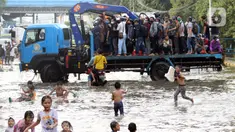 Pekerja kawasan Pelabuhan Nizam Zachman, Muara Baru menumpang kendaraan besar untuk melintasi genangan banjir rob, Jakarta, Jumat (5/6/2020). Banjir rob di Pelabuhan Muara Baru tersebut terjadi akibat cuaca ekstrem serta pasang air laut. (Liputan6.com/Helmi Fithriansyah)
