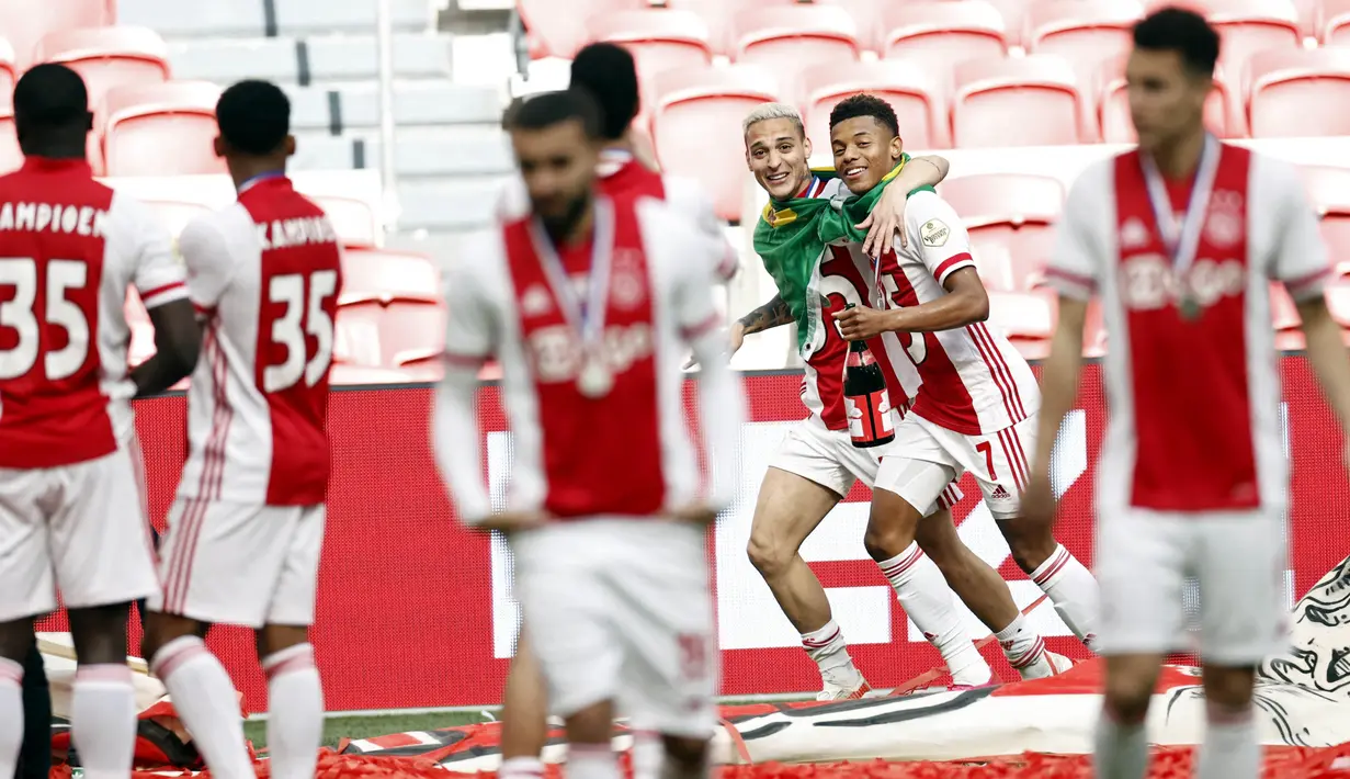 Pemain Ajax Amsterdam, Antony Matheus Dos Santos dan David Neres, melakukan selebrasi usai memastikan diri meraih gelar juara Liga Belanda usai mencukur Emmen 4-0 dalam laga pekan ke-31 di Stadion Johan Cruijff Arena, Minggu (2/5/2021). (AFP/Maurice Va Steen)