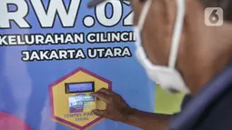 Warga menempelkan kartu pada mesin ATM saat mengambil bantuan beras di Kantor RW 02, Kelurahan Cilincing, Jakarta Utara, Rabu (17/3/2021).  Program ini dibagikan secara berkala selama 2 kali dalam sebulan dengan jatah masing-masing 3 kilogram beras per orang. (merdeka.com/Iqbal S. Nugroho)