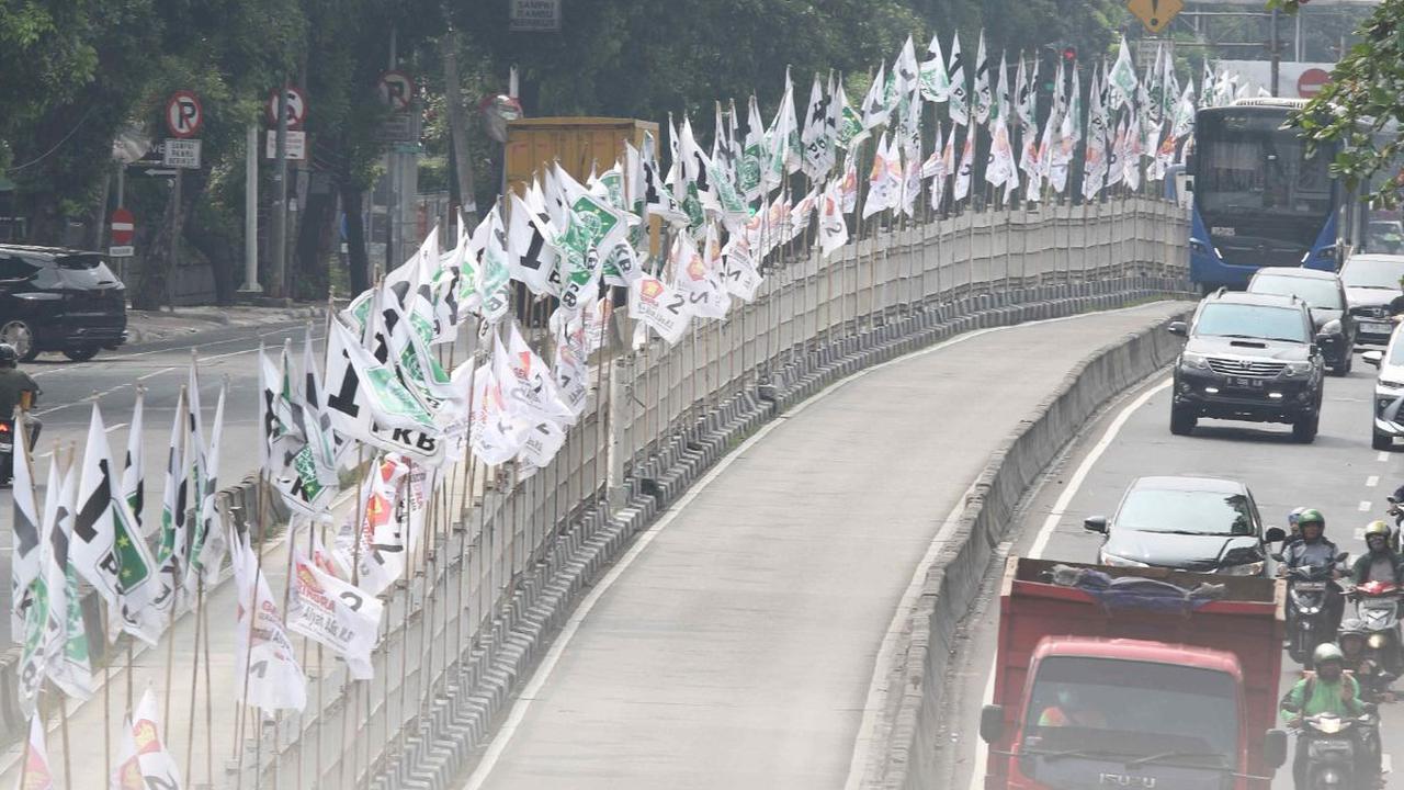 Meskipun masa kampanye belum dimulai, keberadaan atribut bendera partai pada pembatas jalan bisa saja membahayakan pengguna jalan.