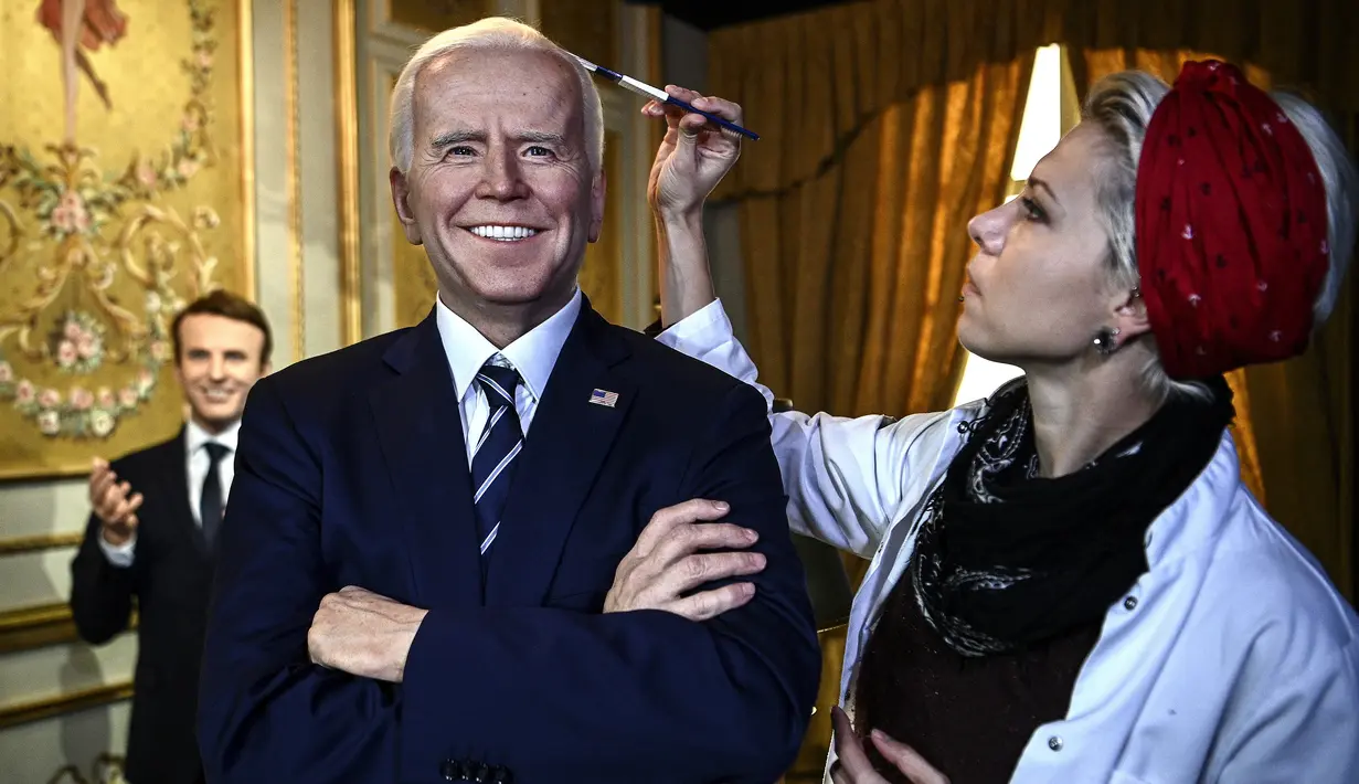 Penata rias memberikan sentuhan akhir pada patung lilin Presiden AS Joe Biden yang baru diresmikan di museum lilin Musee Grevin di Paris, Selasa (18/5/2021). Museum tersebut diperkirakan akan dibuka kembali pada 19 Mei 2021 setelah ditutup berbulan-bulan karena COVID-19. (Christophe ARCHAMBAULT/AFP)