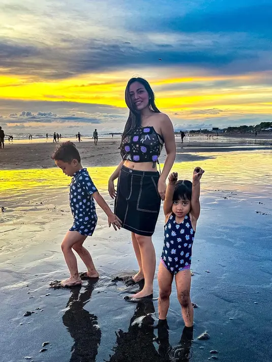 Kali ini Rachel Vennya berpose di pantai bersama kedua anaknya. Abang dan anak bungsunya kompak mengenakan swimsuit dengan motif yang kembar, sedangkan Rachel Vennya memiliki off-the shoulder top bermotif serasi, dan rok denim hitam selutut. Foto: Instagram.