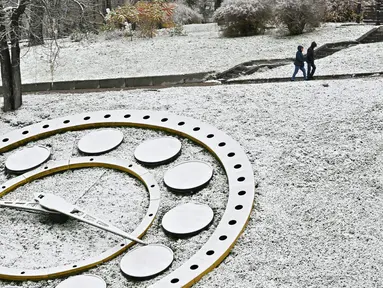 Pejalan kaki berjalan dekat Independence Square setelah salju pertama turun musim ini di Kiev, Ukraina, 17 November 2022. Salju pertama musim ini turun di tengah invasi Rusia ke Ukraina. (Sergei SUPINSKY/AFP)