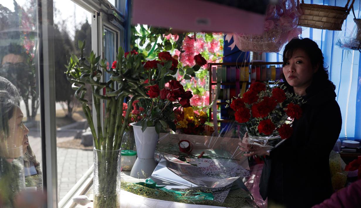 Seorang pedagang menyiapkan karangan bunga untuk pelanggan ketika sejumlah wanita menandai Hari Perempuan Internasional di Pyongyang, Korea Utara, Jumat (8/3). (AP Photo/Dita Alangkara)