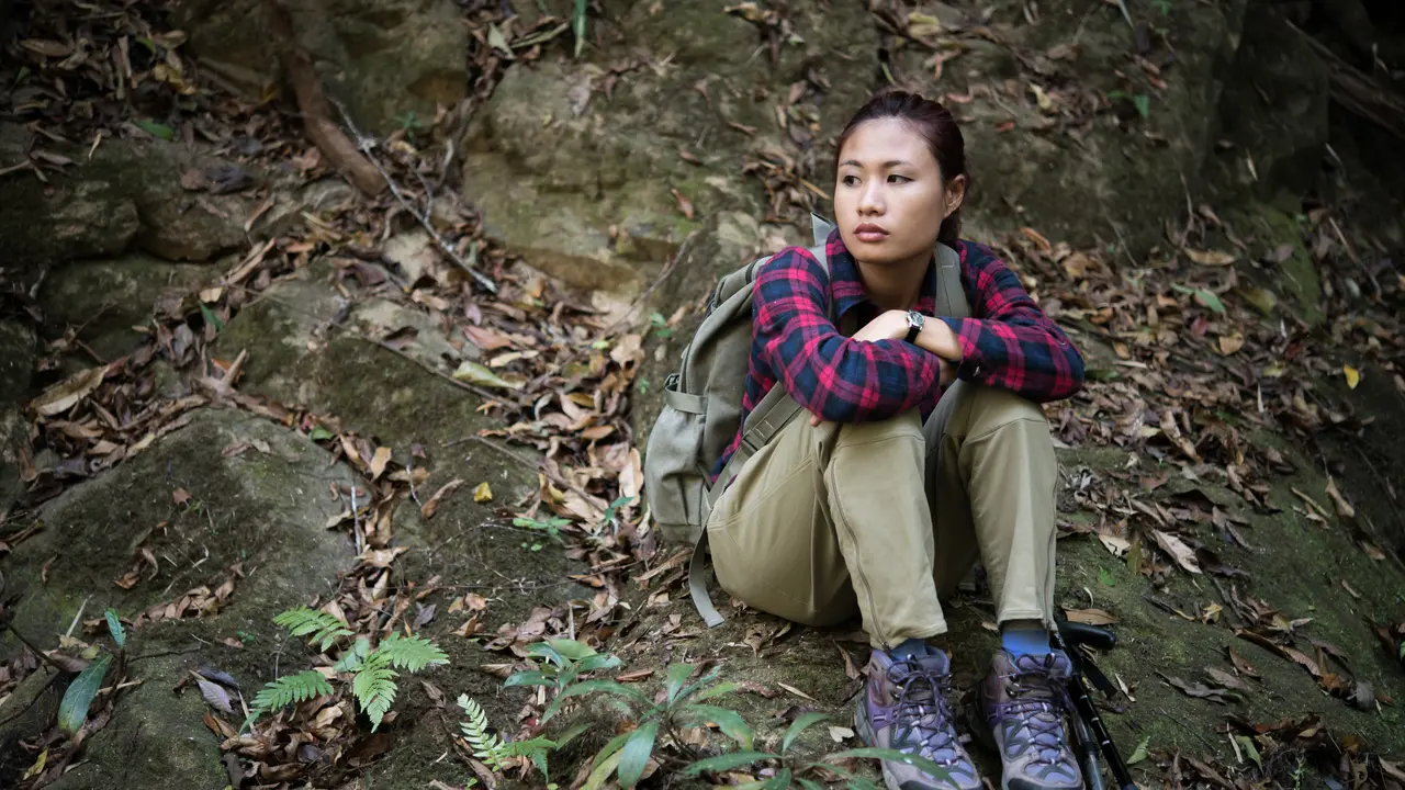 Seorang perempuan sedang duduk dan beristirahat saat mendaki gunung (Foto Dok: Freepik/jcomp)