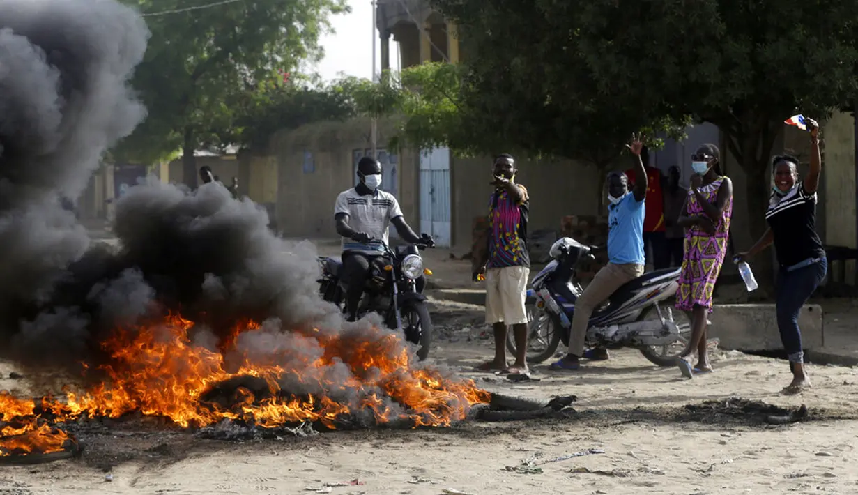 Orang-orang melakukan protes dekat kobaran api di N'Djamena, Chad, Selasa (27/4/2021). Ribuan orang melakukan protes dan dua orang tewas dalam demonstrasi menentang aturan dewan militer transisi yang dipimpin putra Presiden Idriss Deby Itno yang terbunuh minggu lalu. (AP Photo/Sunday Alamba)