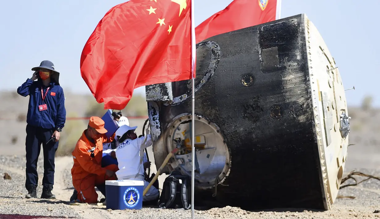 Para pekerja membuka kapsul pesawat ruang angkasa berawak Shenzhou-12 setelah berhasil mendarat di lokasi pendaratan Dongfeng di Daerah Otonomi Mongolia Dalam, China, 17 September 2021. Trio astronot China kembali ke Bumi setelah 90 hari tinggal di Stasiun Luar Angkasa. (Ren Junchuan/Xinhua via AP)